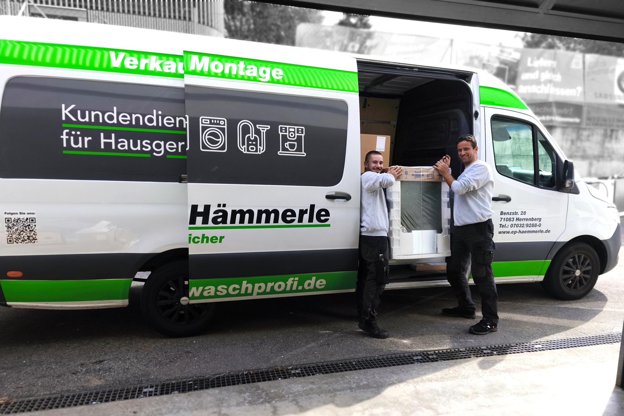Zwei Männer die eine Geschirrspülmaschine in den firmeneigenen Lieferwagen heben und dabei lächeln.